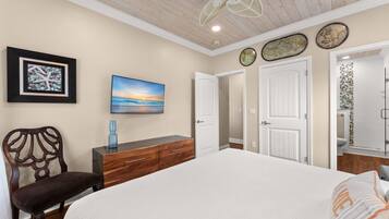 Quarto com cama, cômoda, cadeira, ventilador de teto e obras de arte nas paredes.