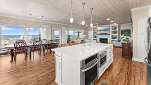 A spacious kitchen with a large island, wooden flooring, and pendant lighting. - Beachfront House - Casa Bella Del Sol (Port St. Joe)
