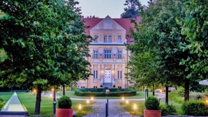 A large, stately building with a symmetrical facade, a central entrance, and a well-maintained garden with a paved pathway leading to the entrance. - Sunday Resort Rugen 1-bedroom Apartment (Sagard)