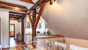 Un coin repas avec une table en bois rustique, des chaises blanches et un panier tressé.