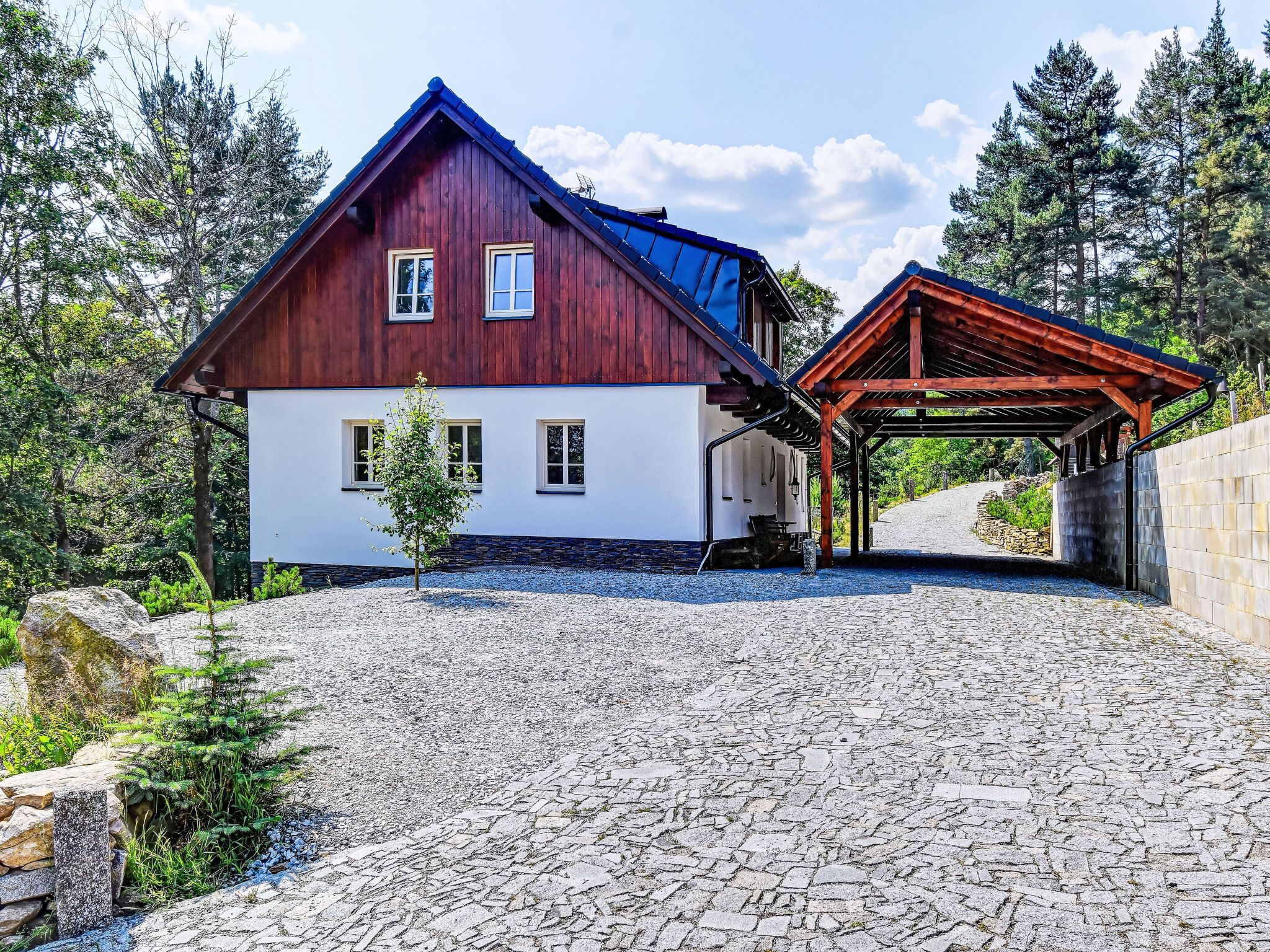 Una casa de madera con fachada blanca, un porche cubierto y un camino de entrada de piedra.