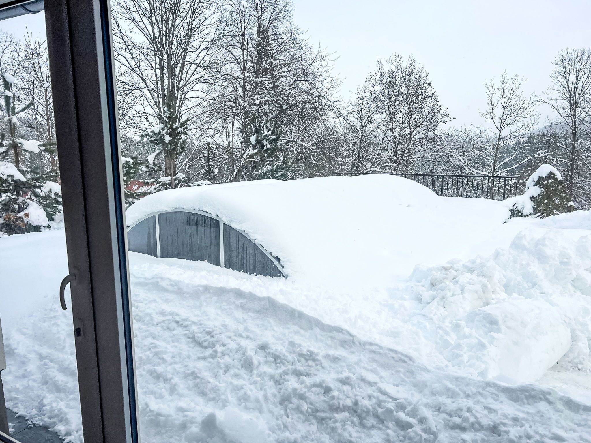 Een besneeerd landschap met een metalen constructie, deels bedolven onder de sneeuw.
