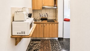 A compact kitchen with wooden cabinets, a built-in microwave, and a sink. - Ein Apartment im Ferienhaus Zweirosen by Interhome (Fažana)