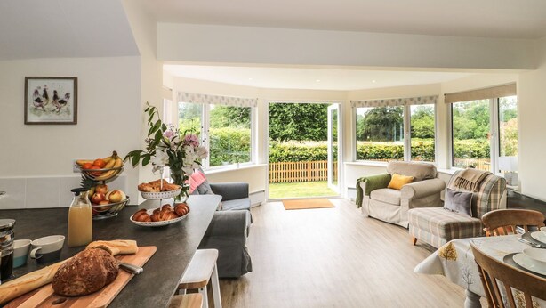 A spacious living area with a kitchen, a dining table, and a comfortable seating arrangement. - Ammerham Farm Cottage (Chard)