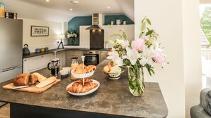A modern kitchen with a central island, a built-in oven, and a large window. - Ammerham Farm Cottage (Chard)