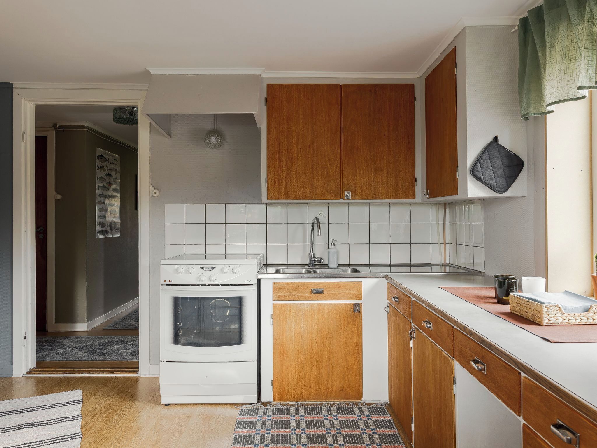 A compact kitchen with white cabinets, a stove, and a sink.