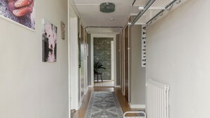 A hallway with a patterned rug, a radiator, and a door leading to another room.
