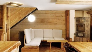 Interior de madera con un banco empotrado, una chimenea y un comedor.
