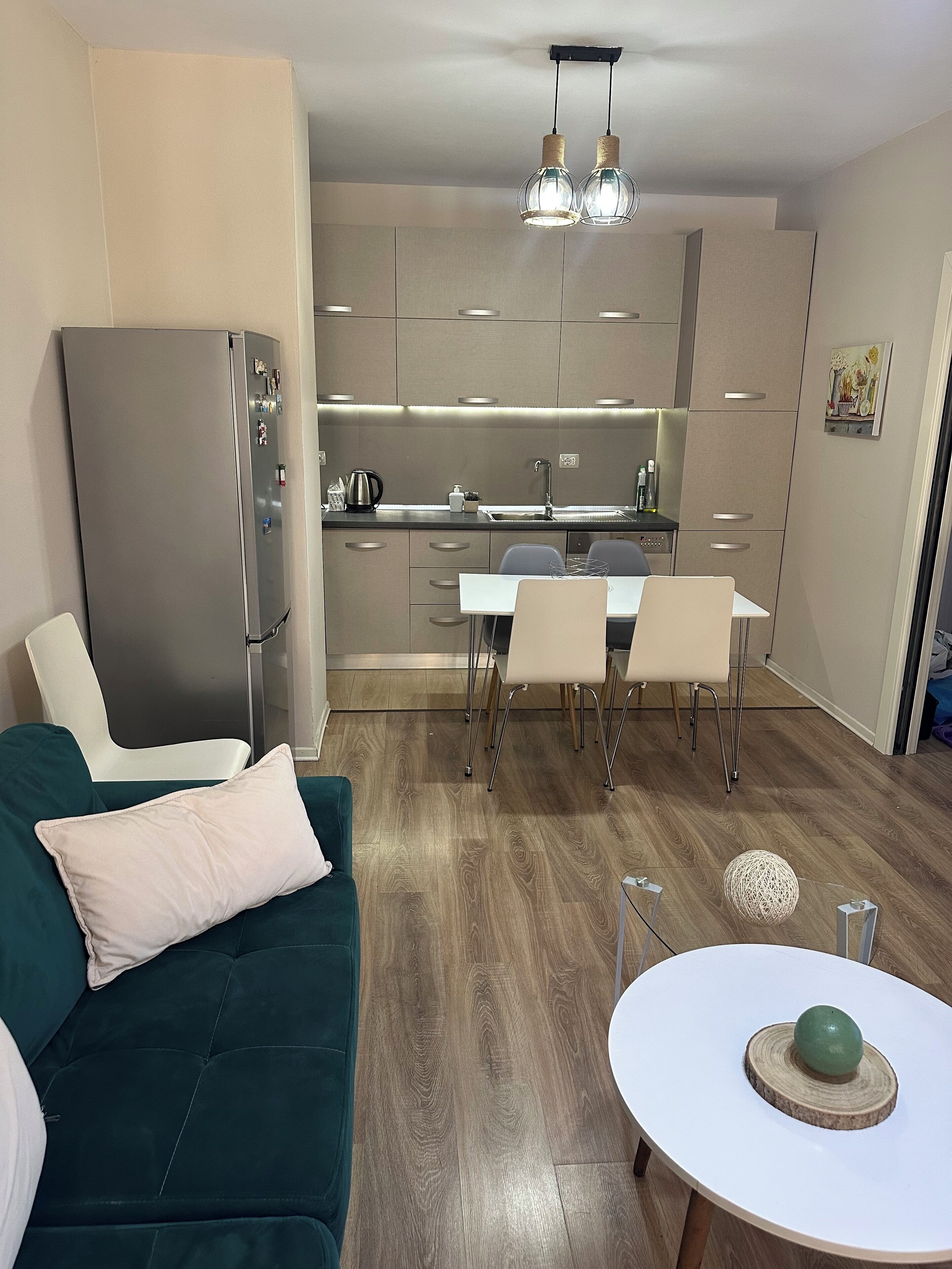 A modern kitchen with a dining area, a sofa, and a round table with a decorative item.