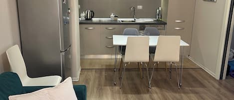 A modern kitchen with a dining area, a sofa, and a round table with a decorative item.