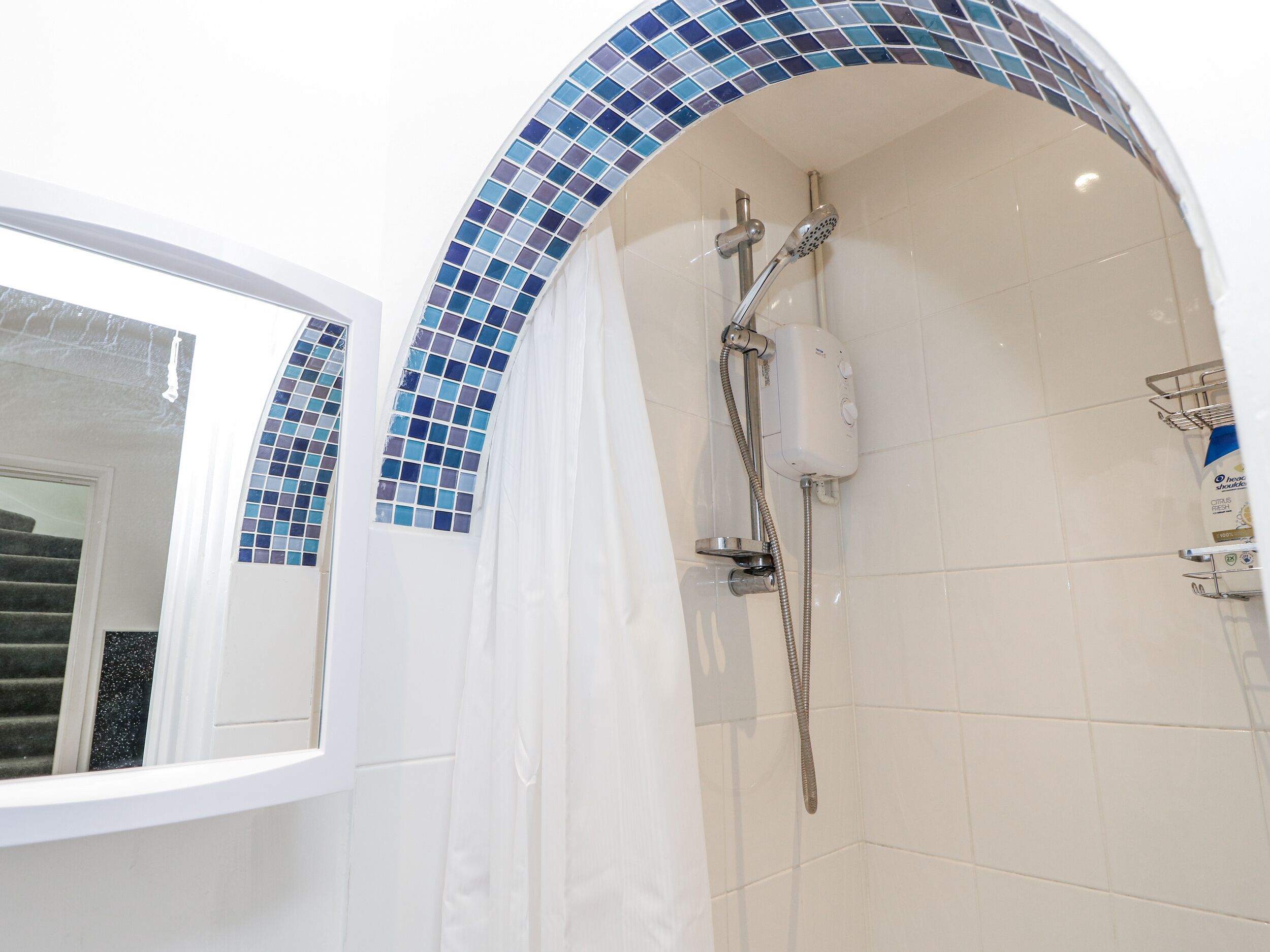 A bathroom with a shower, tiled walls, and a window.