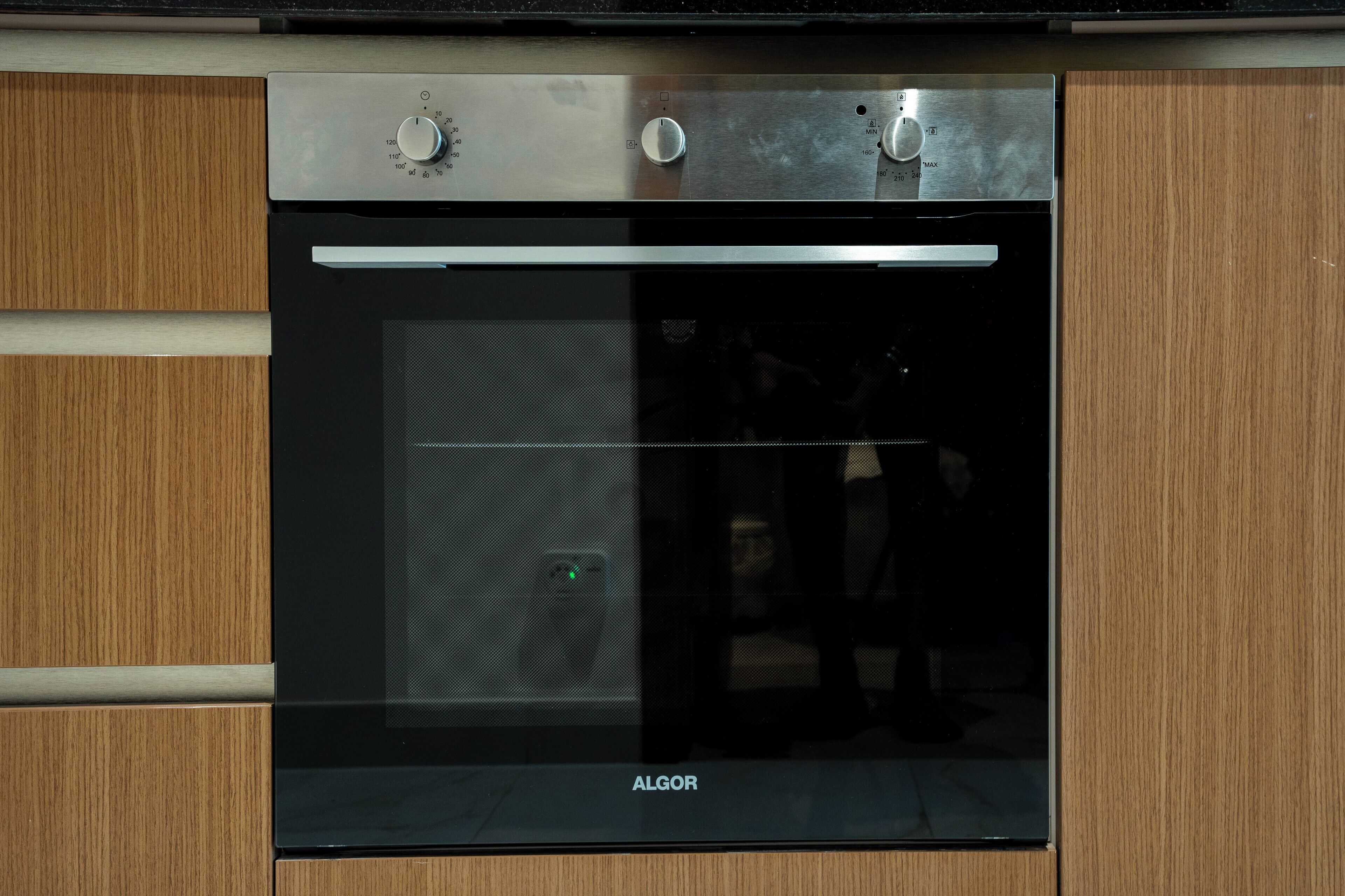 Een keuken met een inbouwoven en twee bedieningsknoppen.