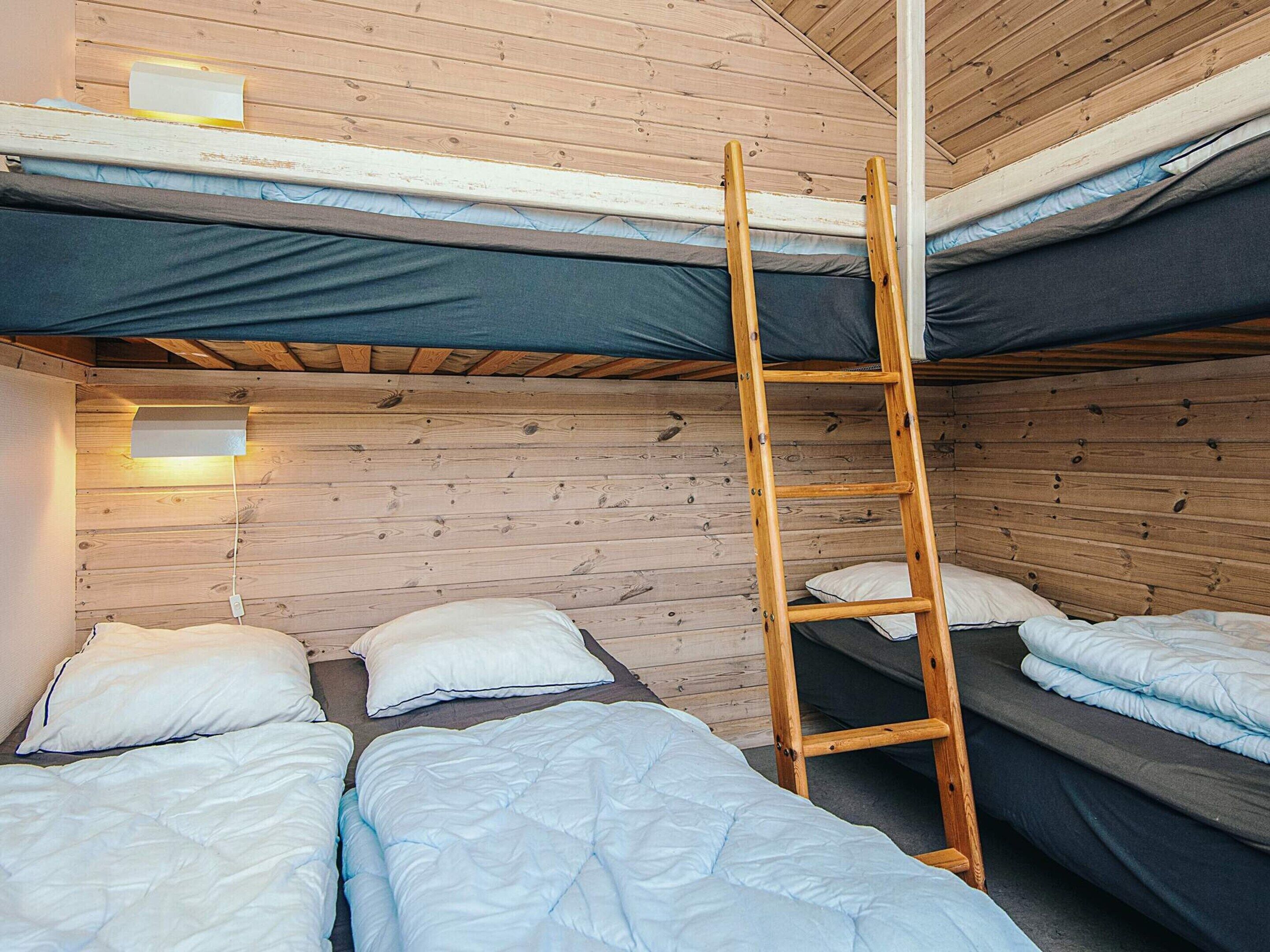 A compact room with bunk beds, a ladder, and a wall-mounted light fixture.