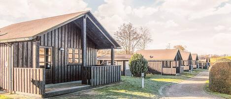 A row of wooden cabins with a porch and a gravel path leading to them.