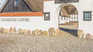 A rustic building labeled "Strandgård Camping" with a thatched roof and a stone wall. - Standard Cabin For, 5 Pers, 25m2 (Ronde)