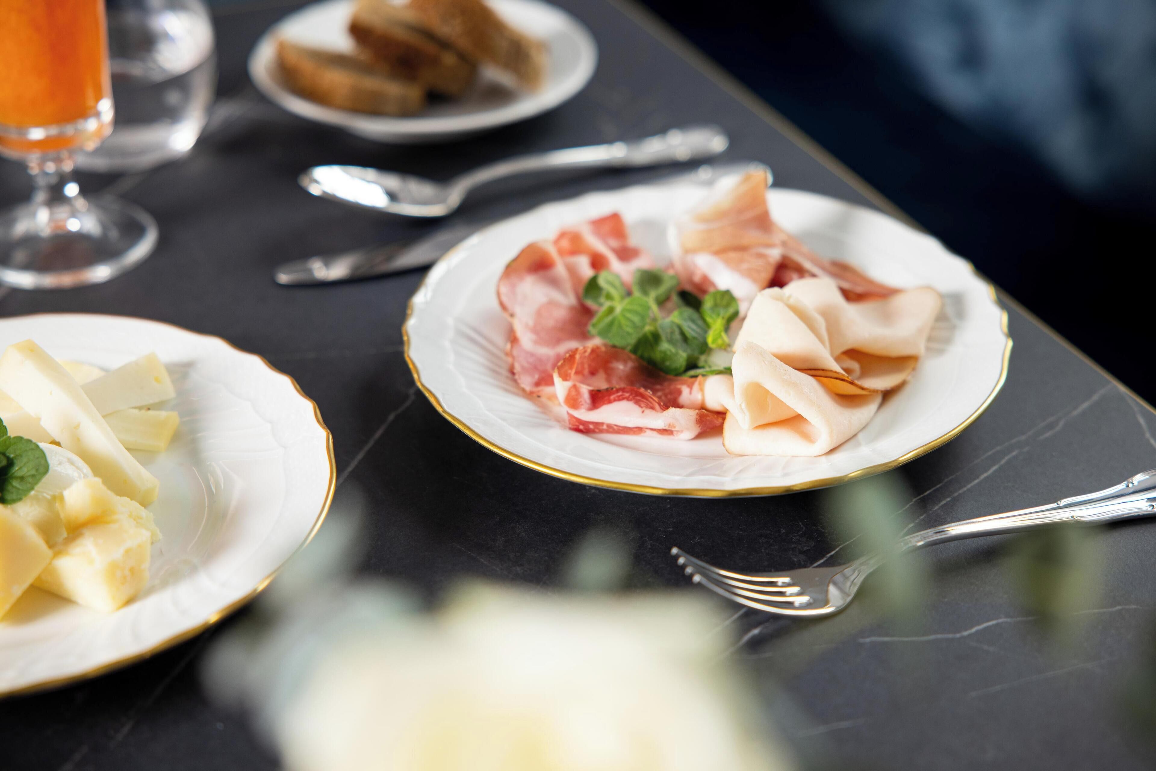 A table with plates of food, a glass of orange juice, and cutlery.