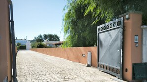 Ein gepflasterter Weg führt zu einem verschlossenen Eingang mit einem Metalltor und einer Mauer mit einem kleinen Fenster.