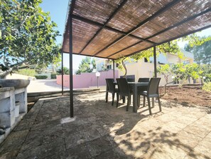 An outdoor patio with a covered seating area, stone flooring, and surrounding greenery. - Apartment Giove by Interhome (Torre Vado)