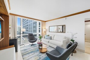 Ein modernes Wohnzimmer mit einer Couch, Sesseln, einem Couchtisch und einem großen Fenster mit Blick auf die Stadt.