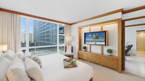 Ein Hotelzimmer mit einem großen Bett, einem Wandfernseher und Blick auf die Stadt.