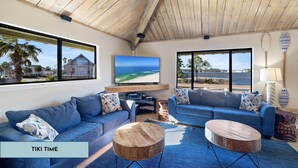 Uma sala de estar moderna com uma televisão grande, dois sofás e uma mesa de centro de madeira.