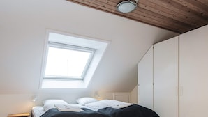 Ein Schlafzimmer mit Dachfenster, einem Bett, einem Kleiderschrank und einem Nachttisch.