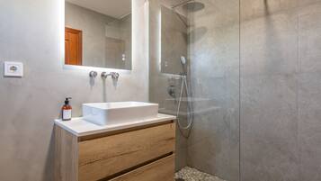 Une salle de bain moderne avec un lavabo blanc, un meuble-lavabo en bois et une douche séparée par des parois en verre.