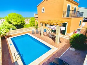 Ein Pool mit Pergola, Gartenmöbeln und einer Steinmauer.