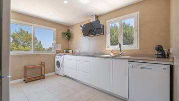 Una cocina moderna con lavadora integrada, lavavajillas y un amplio ventanal que proporciona luz natural.