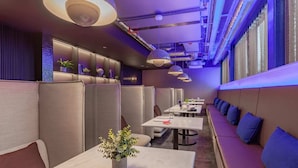Een modern restaurant met zitjes en tafels, waarvan sommige beplant zijn.