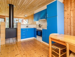 Eine kleine Küche mit blauen Schränken, einem Holztisch und einem schwarzen Herd.