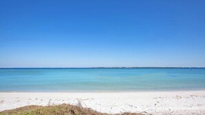 A beach with clear blue water and a sandy shore. - Beautiful, Pet Friendly, Waterfront Townhome at San De Luna #3! (Pensacola Beach)