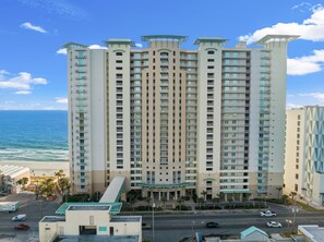Un hotel de altura con varios balcones, piscina y vistas al océano.