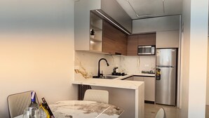 Een moderne keuken met een inbouwmagnetron, een roestvrijstalen koelkast en een marmeren aanrecht.