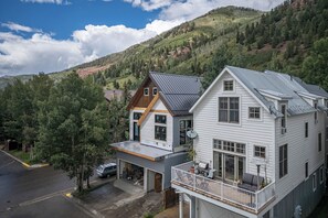 Ein zweistöckiges Haus mit Garage und Balkon, vor einer Bergkulisse.