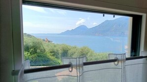 A window view of a mountainous landscape with a body of water. - Appartamento Pozzo (Brenzone sul Garda)