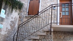 A stone staircase with metal railings leading to a wooden door. - Appartamento Pozzo (Brenzone sul Garda)