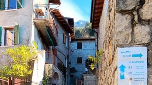 A narrow cobblestone street leading to a building with a sign indicating directions to a garage and an apartment. - Appartamento Pozzo (Brenzone sul Garda)