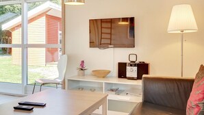 Una sala de estar moderna con un sofá, una mesa, un televisor y una lámpara.
