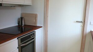 Una cocina compacta con horno empotrado, microondas y cafetera sobre la encimera.