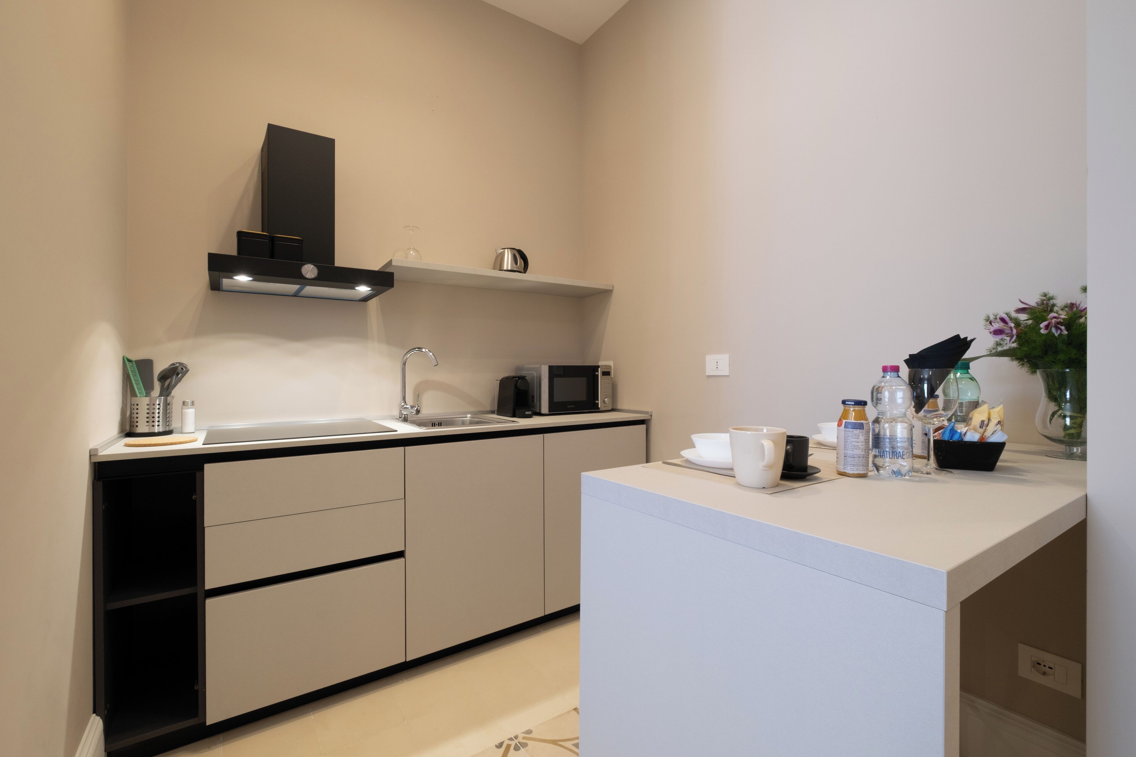 A modern kitchen with a sink, microwave, and a countertop with various items.