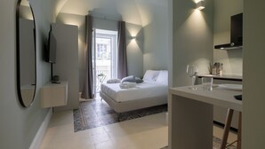 Ett modernt hotellrum med en säng, ett skrivbord, en spegel och en tv.