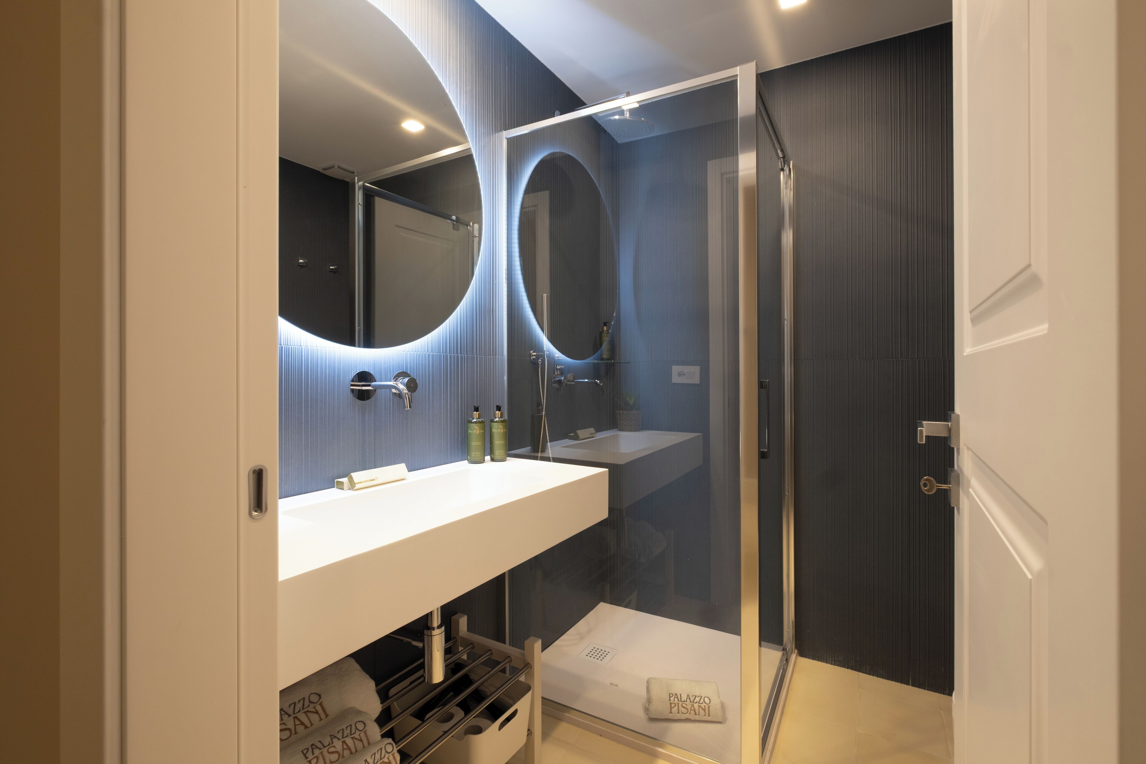 Un bagno moderno con doccia vetrata, mobile lavabo bianco e due grandi specchi.