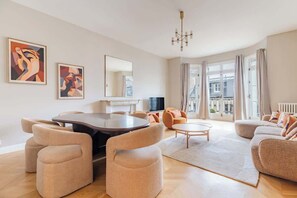 Ein modernes Wohnzimmer mit einem runden Esstisch, bequemen Sofas und Kunstwerken an den Wänden.