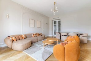 Ein modernes Wohnzimmer mit einer Eckcouch, runden Couchtischen und einem Essbereich mit Stühlen.