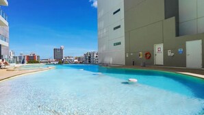Una piscina con agua cristalina, rodeada de edificios modernos y un flotador en la pared.
