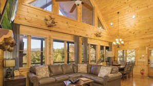Amplia sala de estar con un sofá de cuero grande, techo de madera y ventanas grandes con vistas al exterior.