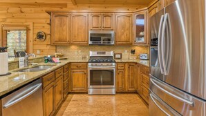 Una cocina con armarios de madera, electrodomésticos de acero inoxidable y encimera de granito.