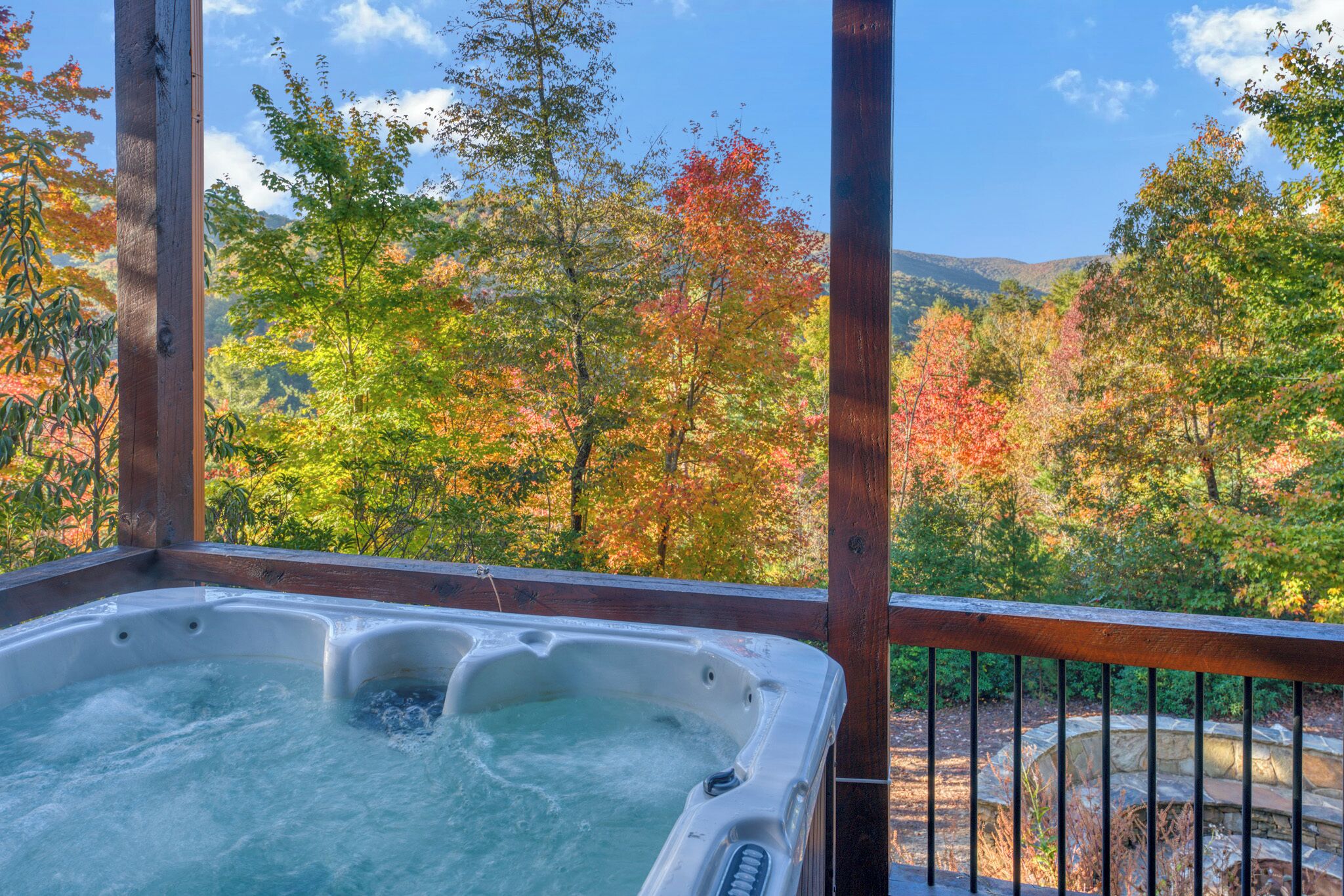A hot tub on a wooden deck with a view of autumn trees.