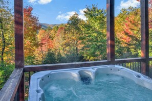 Een hottub met een houten terras en uitzicht op herfstkleuren.